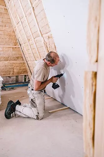 Person mit Bohmaschine arbeitet an einer Wand