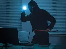 Kompakt Einbruchhemmende Wände Ein Einbrecher mit Taschenlampe steht vor einem Laptop