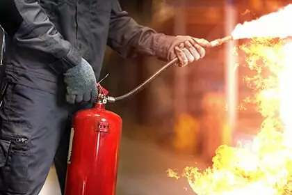 Person löscht Feuer mir Feuerlöscher