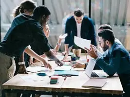 Tools RiAS Mehrere Menschen stehen um einen Tisch und reden